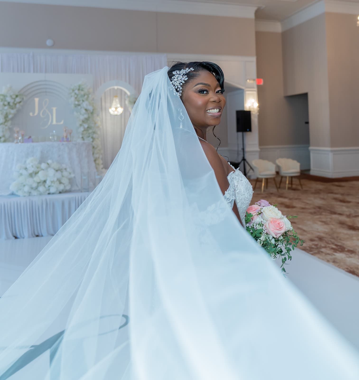 Bride smiling over her shoulder with her veil and bouquet