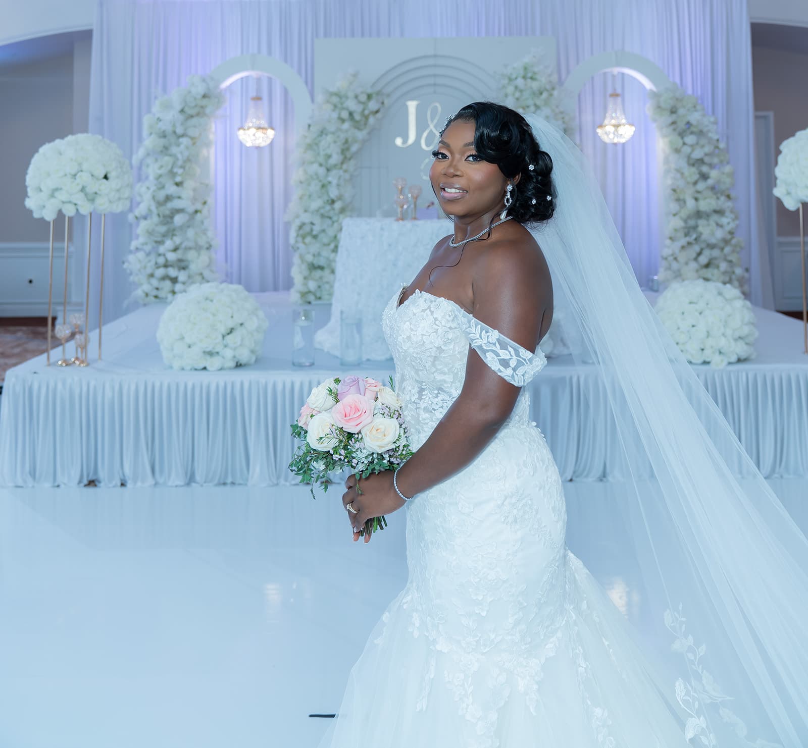 Bride seated in front of white floral wedding decor