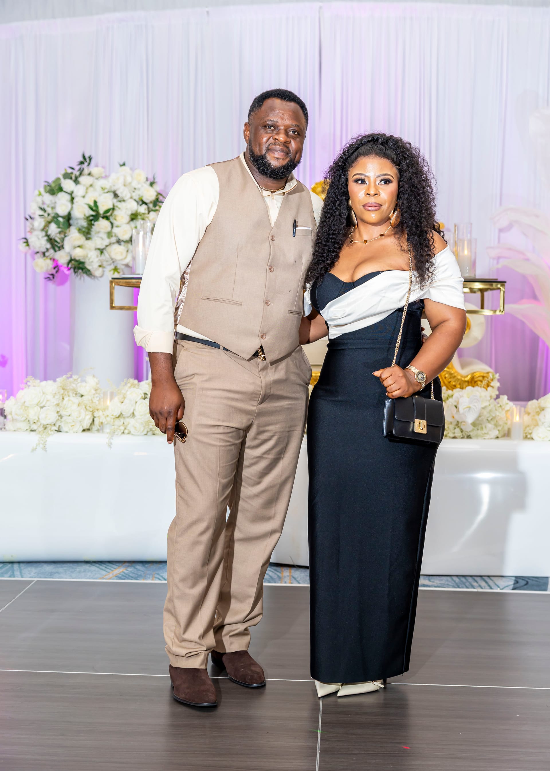 Two wedding guests posing together near a floral backdrop